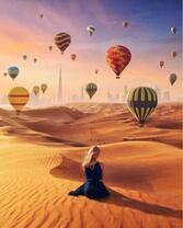 Девушка на песке любуется полетом воздушных шаров